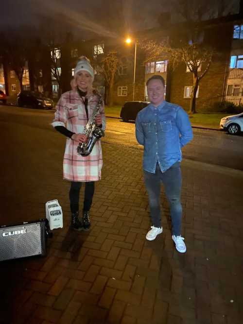 Kay with saxophone stood next to a customer on a driveway