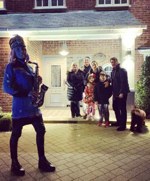 Kay with saxophone stood on driveway with a family