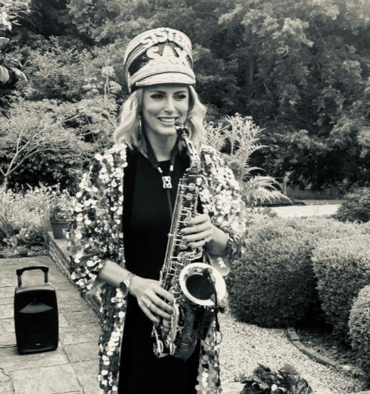 Kay and Lauren stood on dancefloor holding sax at Lauren and Jamie's wedding