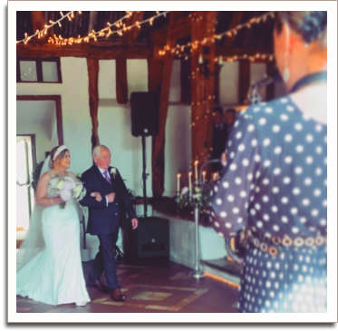 Bride and groom walking down isle with Kay playing Sax in the foreground